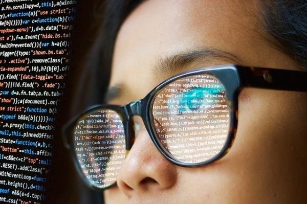 プログラミングコードを見つめる眼鏡をかけた女性